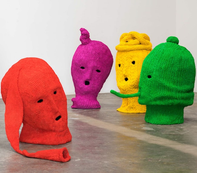 Four colorful knitted head sculptures in a row — Maureen Selwood installation